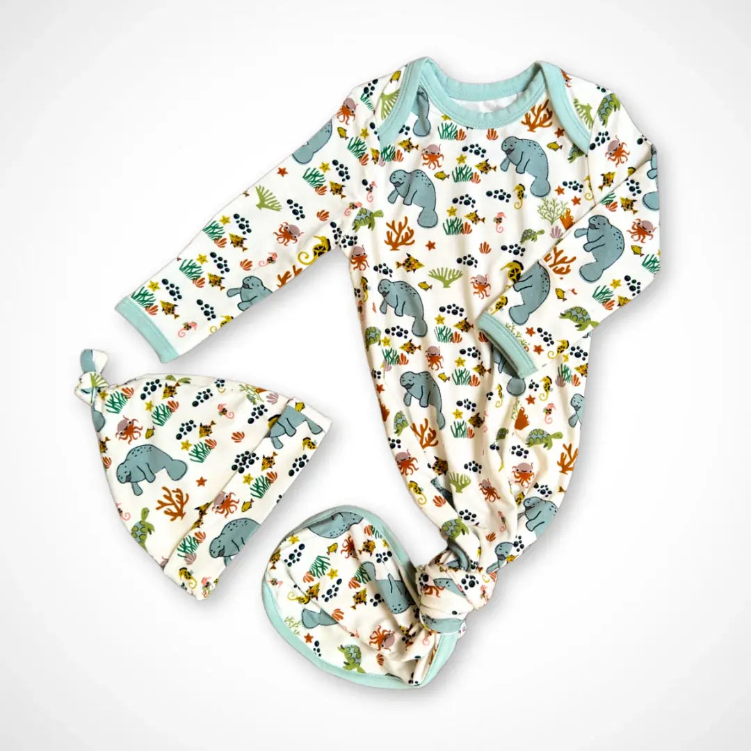 Newborn knotted gown with matching hat in a manatee print, featuring fold-over mitten cuffs and a tied bottom.