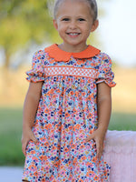 Girls dress with colorful floral print, smocked details, contrasting petals collar, and puffed sleeves