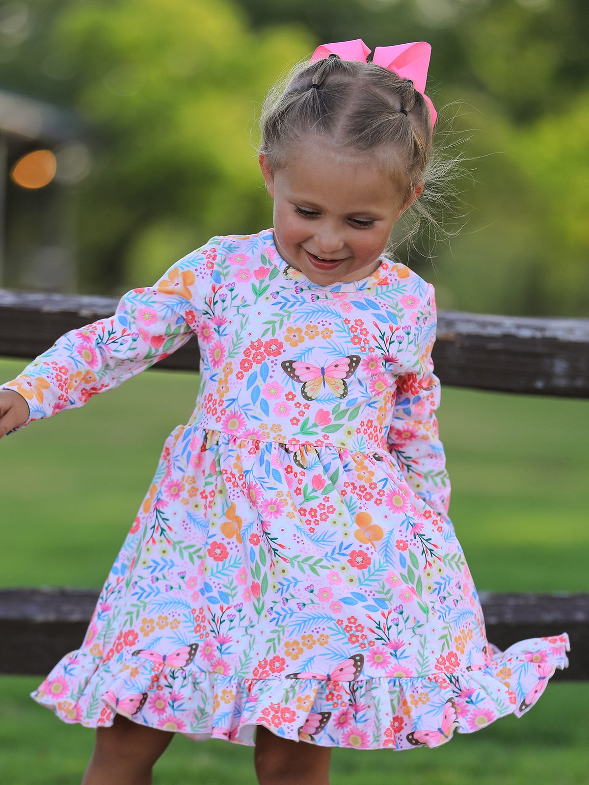 Long-sleeve girls twirl dress with colorful butterfly and floral print and a ruffle hem.