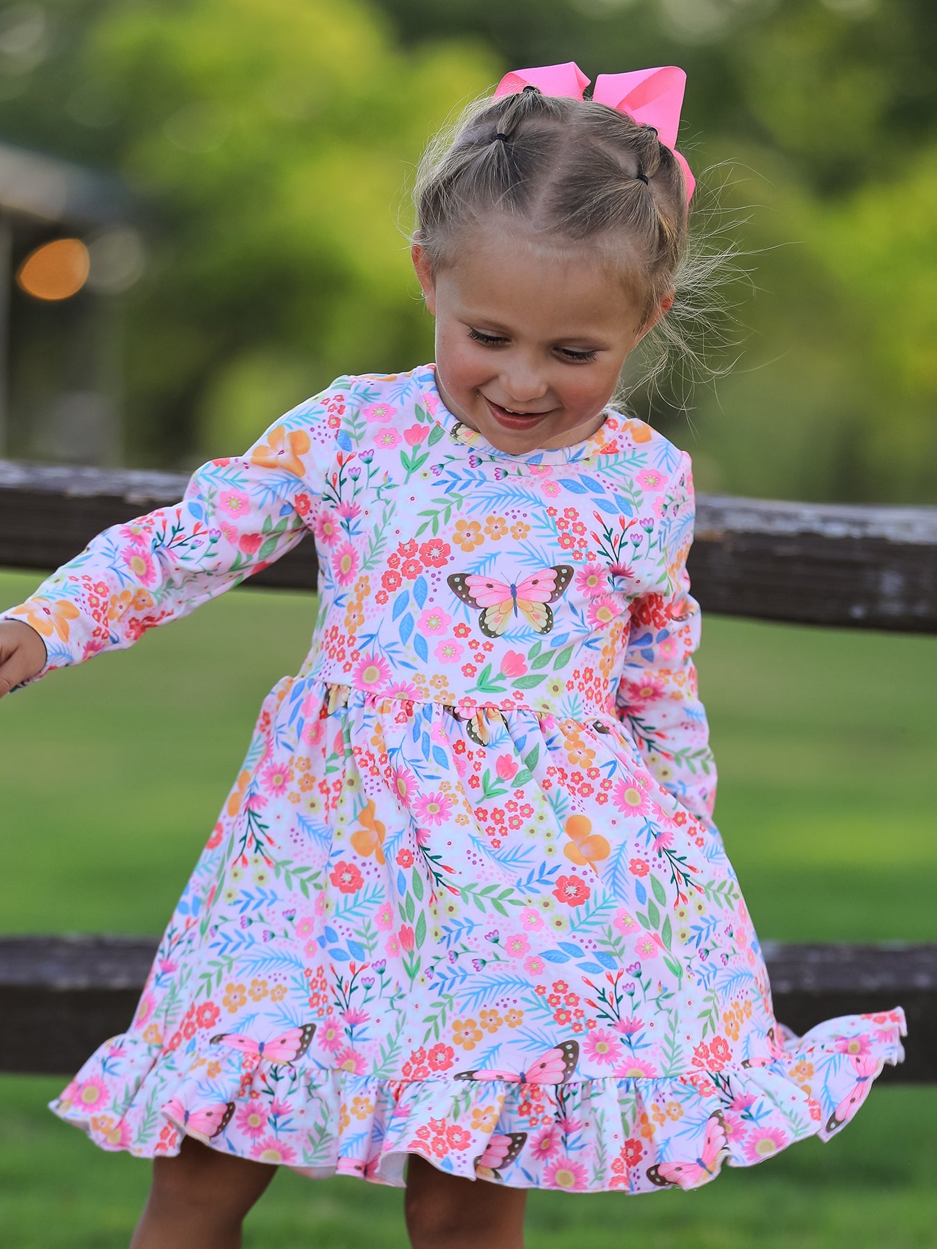 Long-sleeve girls twirl dress with colorful butterfly and floral print and a ruffle hem.