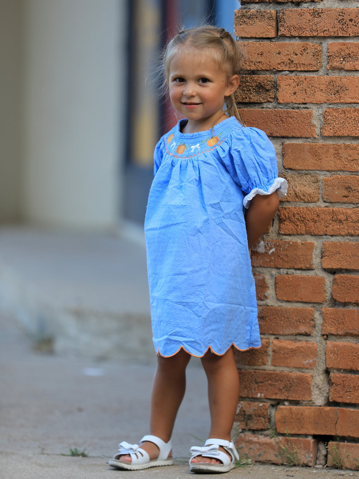 Blue baby girl dress with pumpkin embroidery, lace details, and a smock bodice for fall occasions.