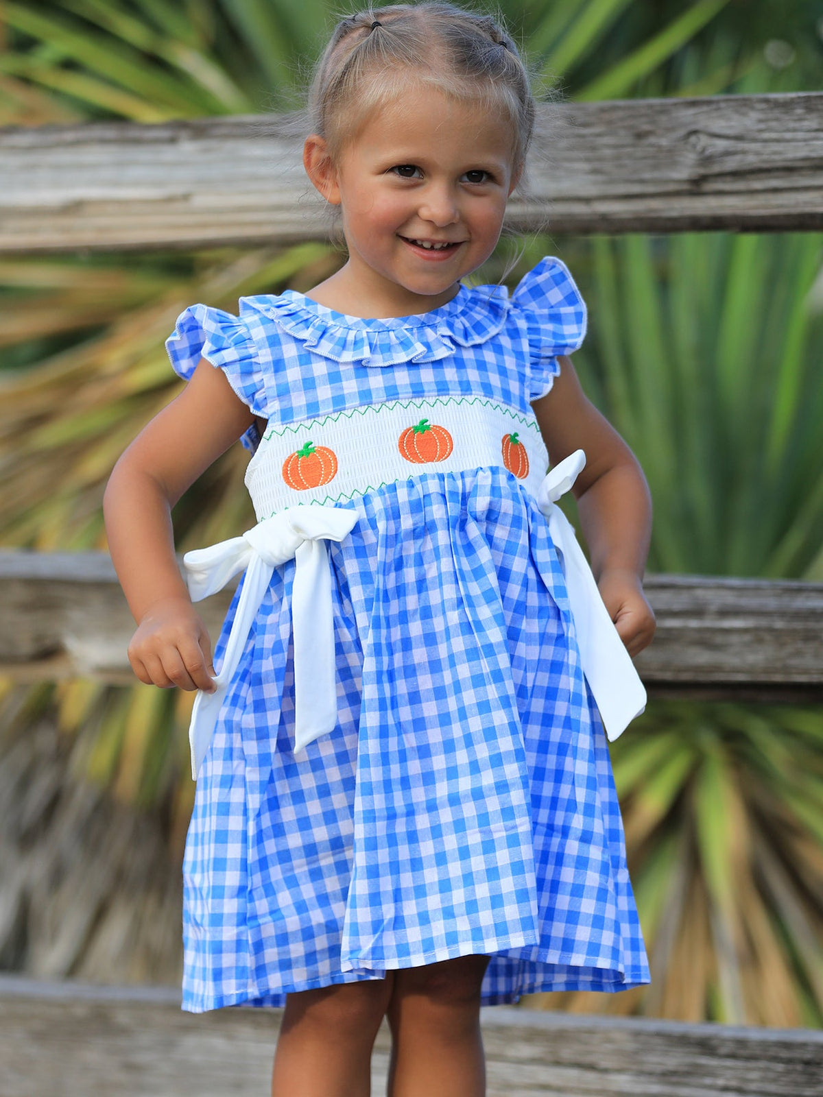 Baby girl dress with blue pumpkin embroidery and a smocked bodice, made in soft cotton for fall celebrations.