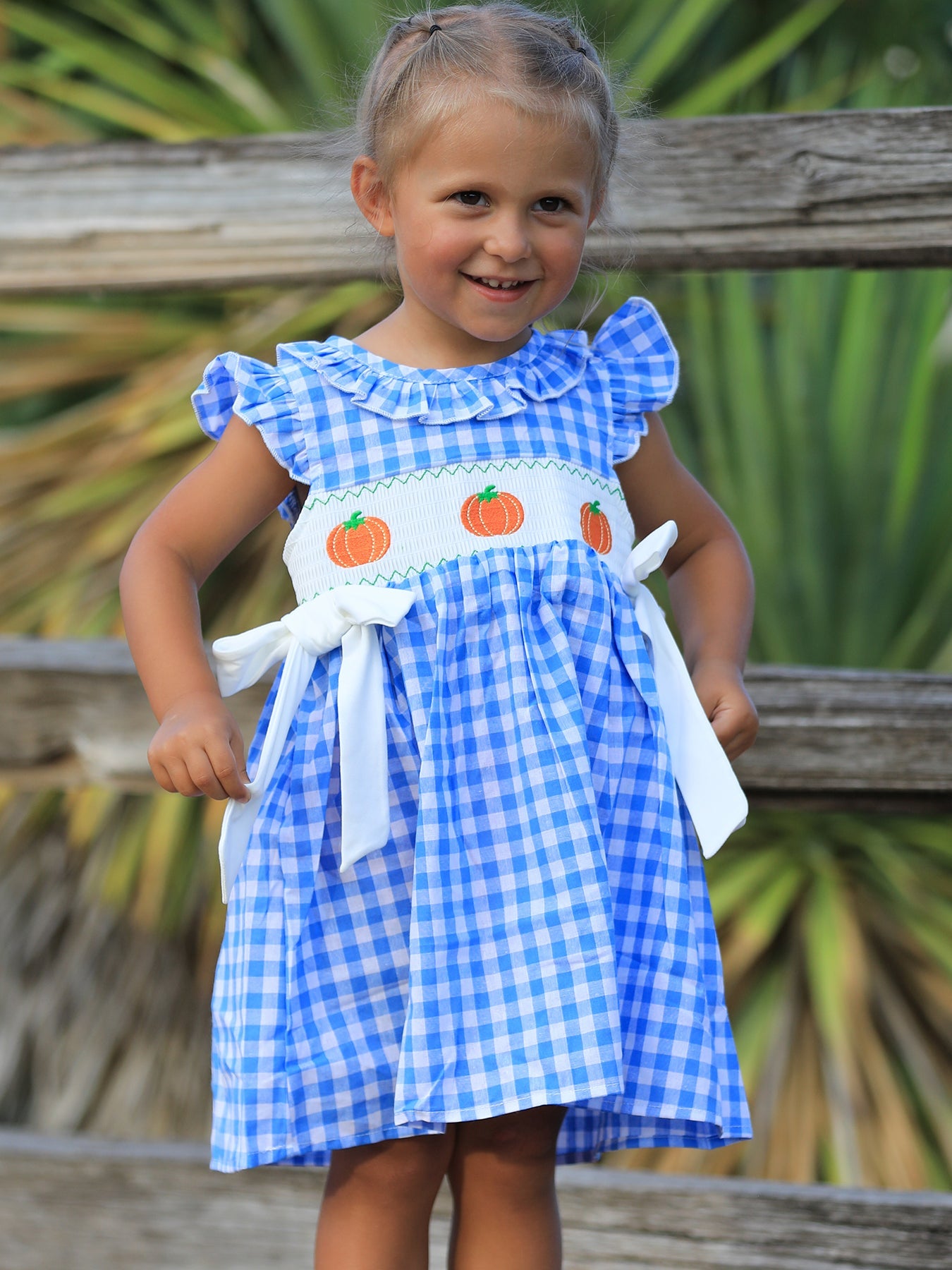 Baby girl dress with blue pumpkin embroidery and a smocked bodice, made in soft cotton for fall celebrations.