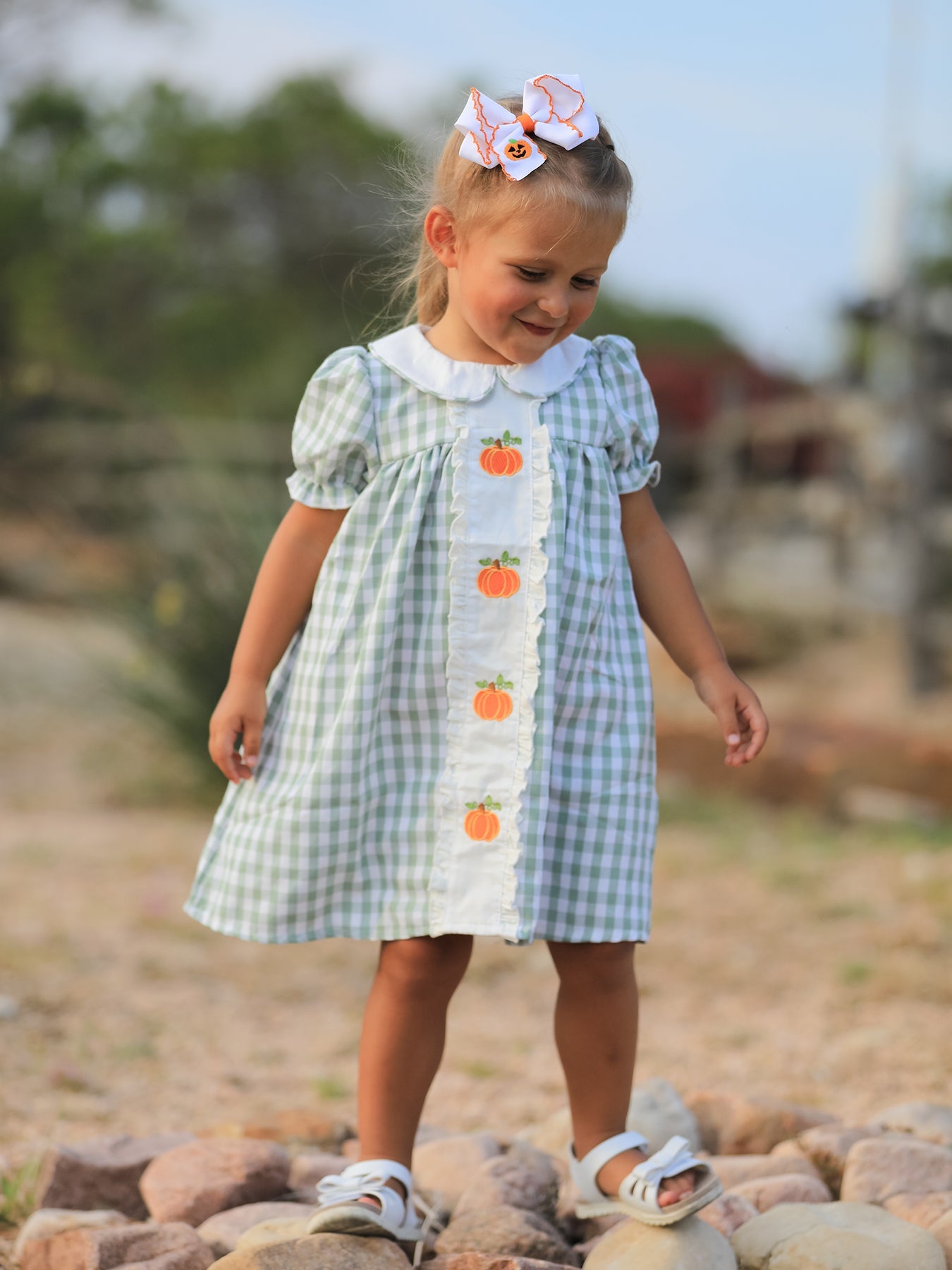 Green plaid girls dress with pumpkin applique details, styled for fall and Thanksgiving.