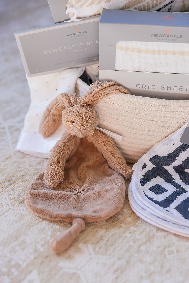Welcome Baby basket with cotton blanket, bamboo swaddle, cozy crib sheet, burp rag, and Rabbit Richie tuttle toy.