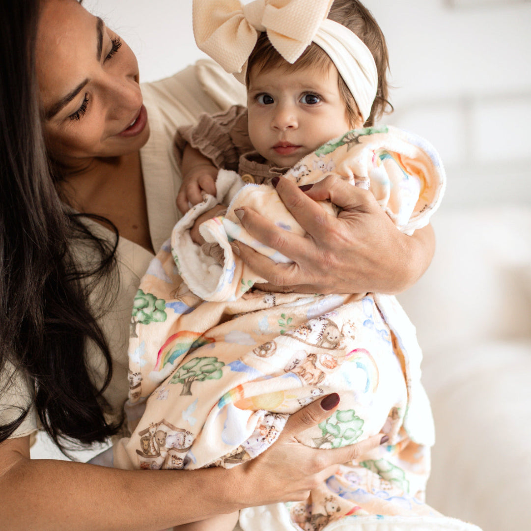 Minky baby blanket with a yellow Noah's Ark front showing lions, elephants, zebras, rainbows, and clouds, and a white back.