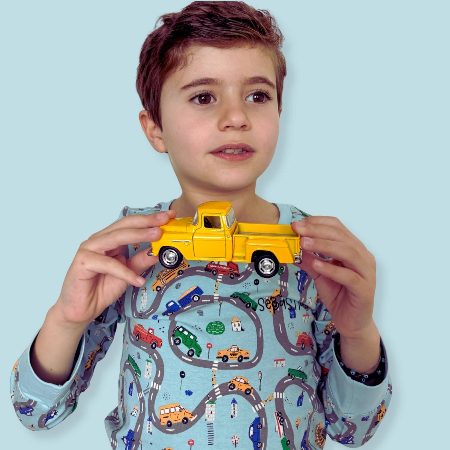 Two-piece long-sleeve kids pajama set with a car print top and matching pants.