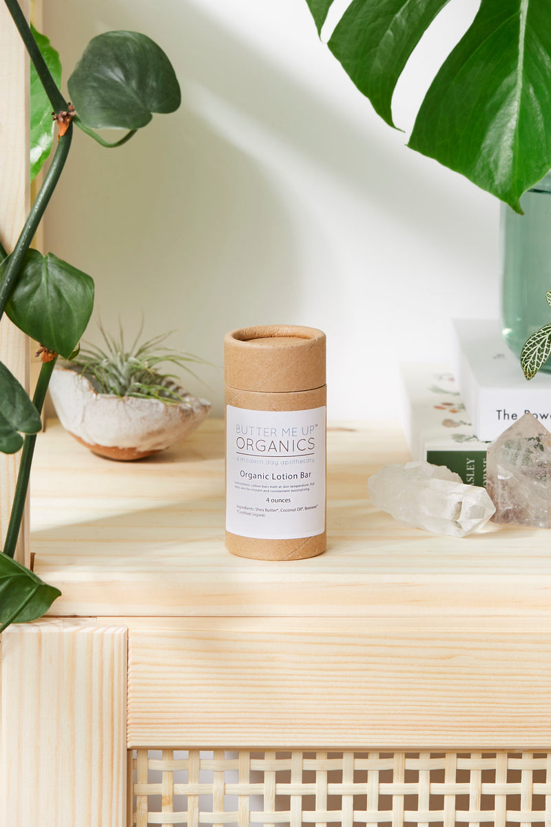 Organic Lotion Bar on wooden shelf, eco-friendly packaging, surrounded by plants.