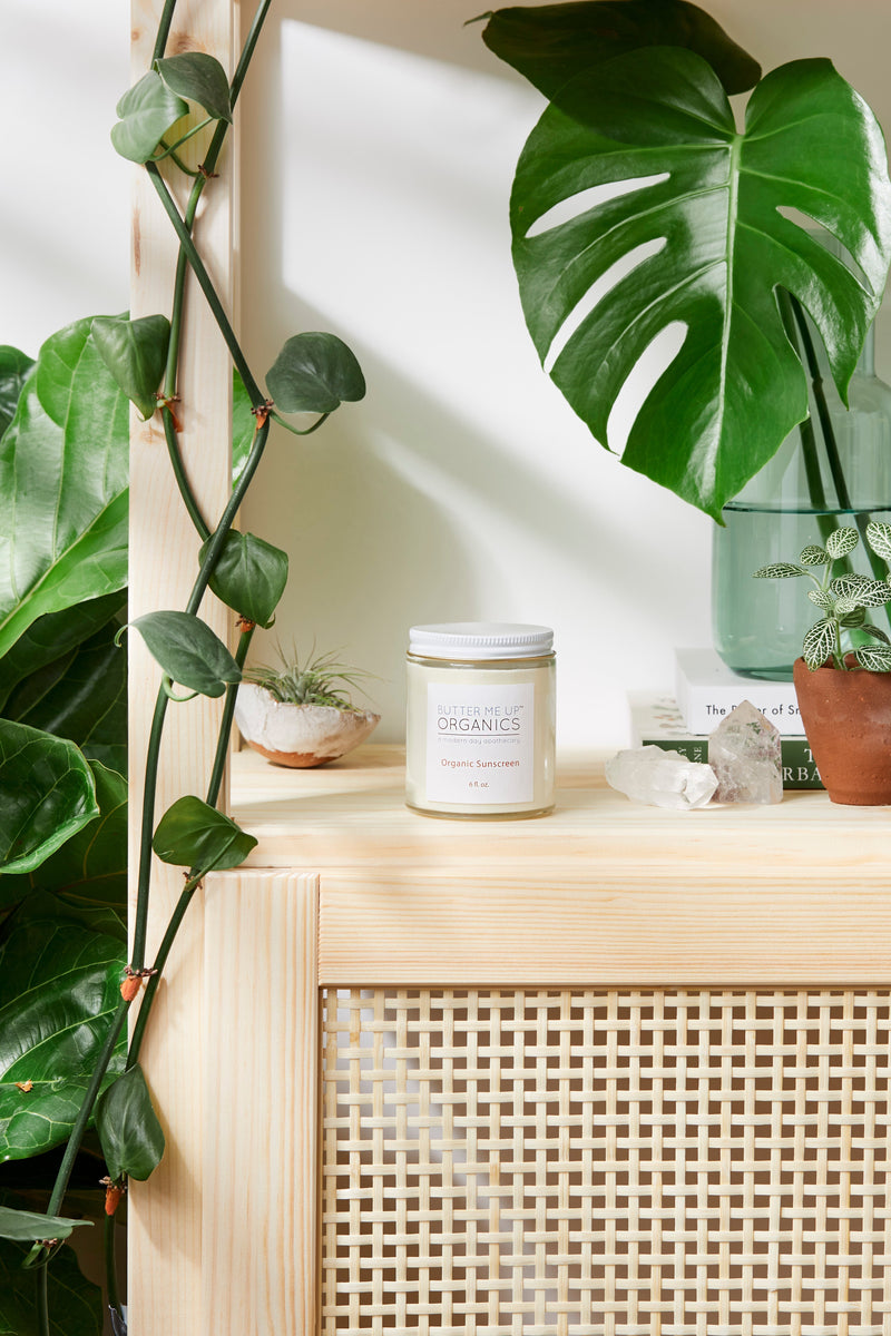 Non-nano zinc oxide sunscreen in glass jar amidst indoor plants and decor.