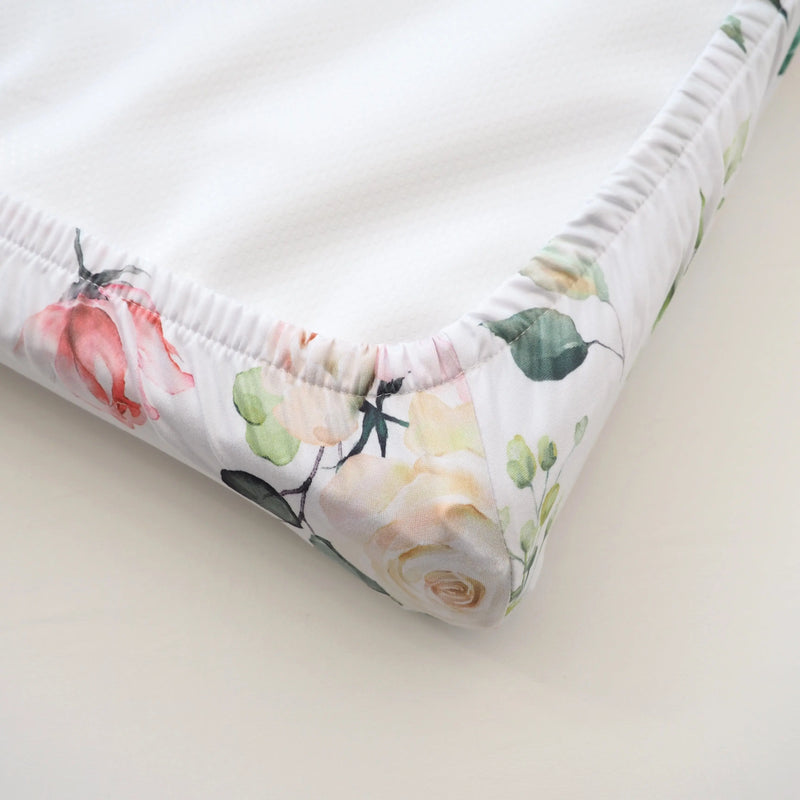 Peach floral changing pad cover on nursery table, soft and stretchy fabric.