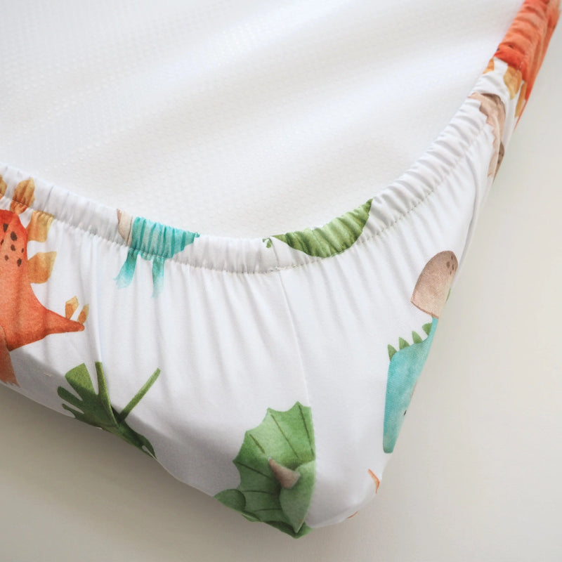 Changing pad cover with dinosaur design, soft and stretchy fabric, fits most pads.