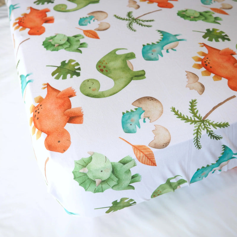 Fitted crib sheet with colorful dinosaur pattern on a standard size mattress.