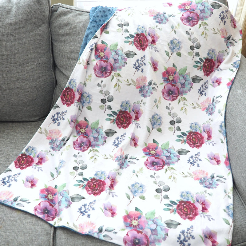 Premium blue floral baby and toddler minky blanket on gray sofa.