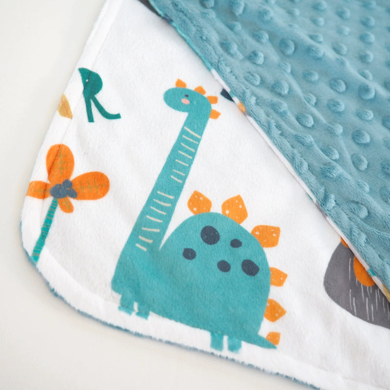 Mini Minky Dinoland Blue toddler blanket with dinosaur print and dot texture.