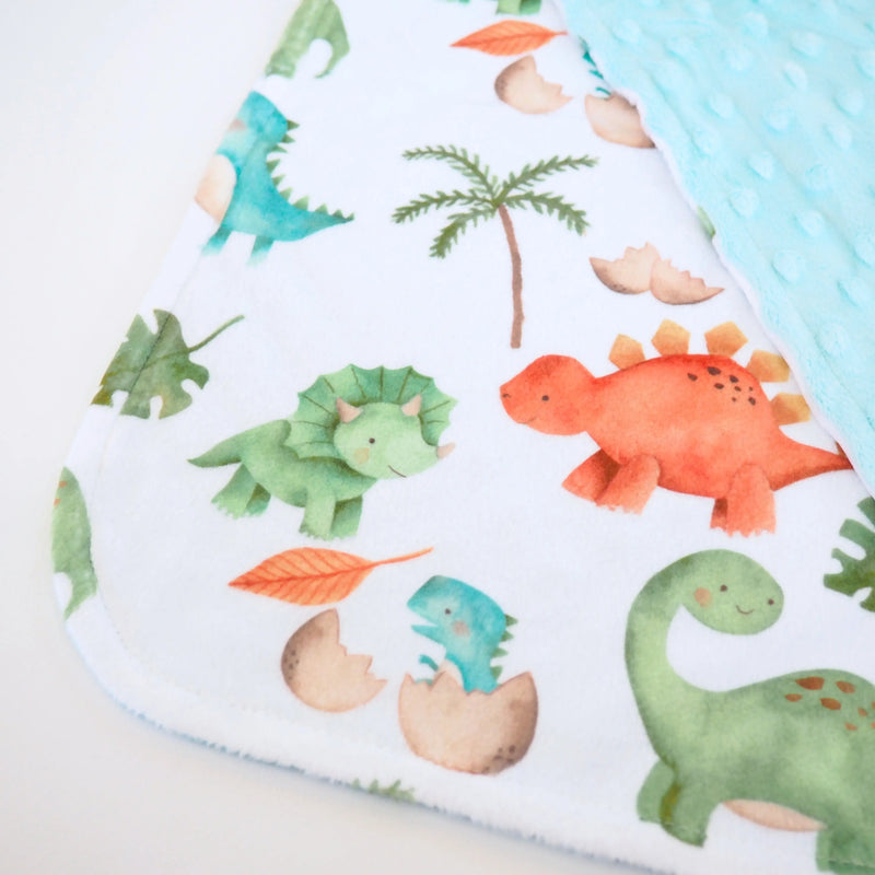 Toddler-sized 'Mini Minky - Dino' blanket with colorful dinosaur pattern, perfect for easy carrying.