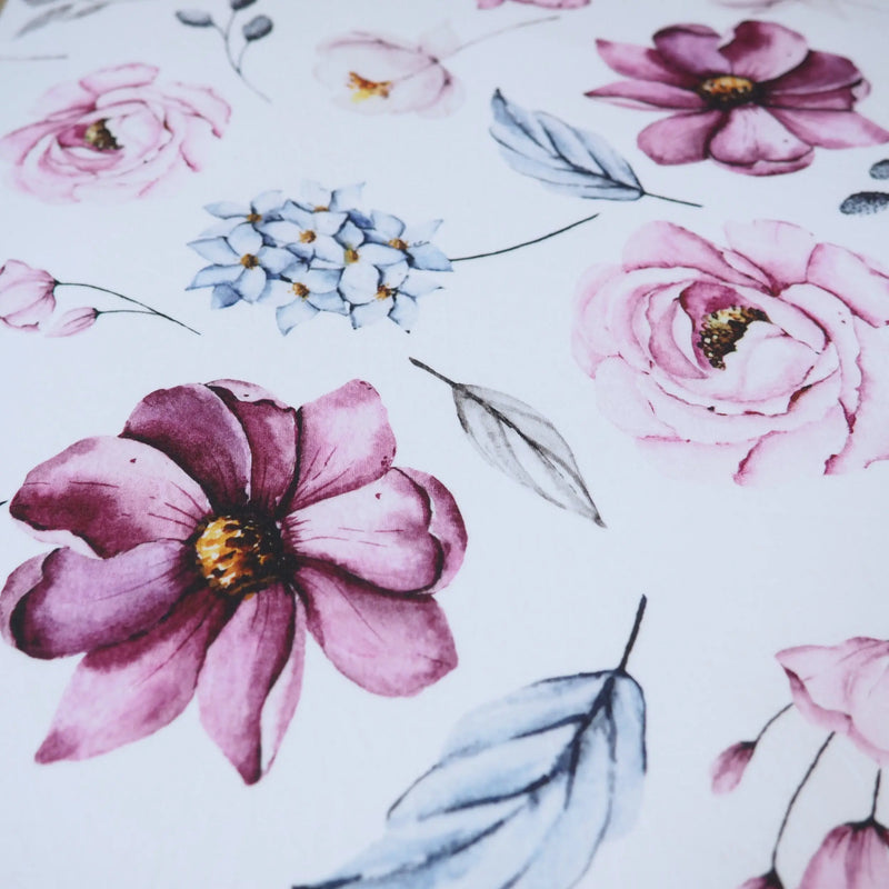Vintage floral fitted crib sheet with soft pink and blue flowers on a white background.