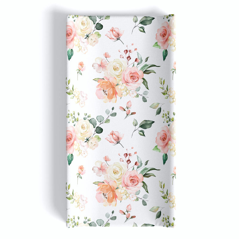 Peach floral changing pad cover with soft, stretchy fabric.
