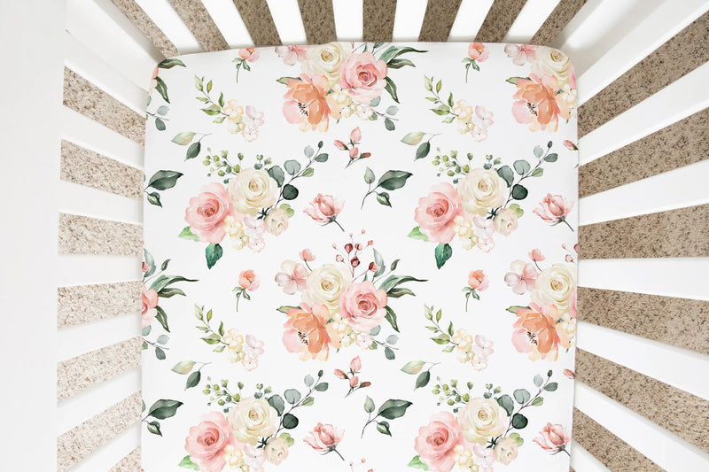 Peach floral fitted crib sheet in a crib.