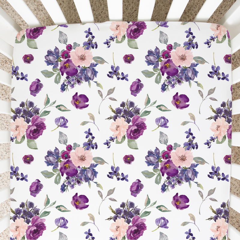 Fitted crib sheet with purple and blush floral pattern in a crib.