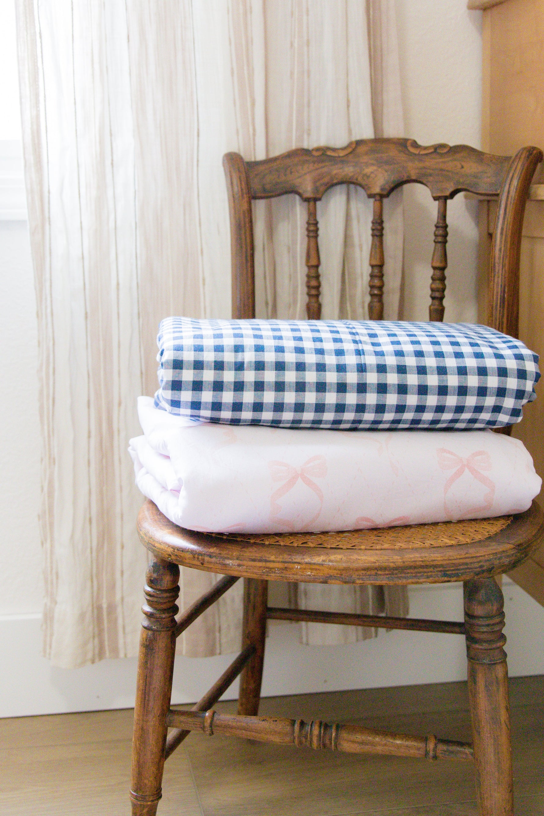 Little Mae & Co organic navy gingham quilted crib blanket draped over a white crib.