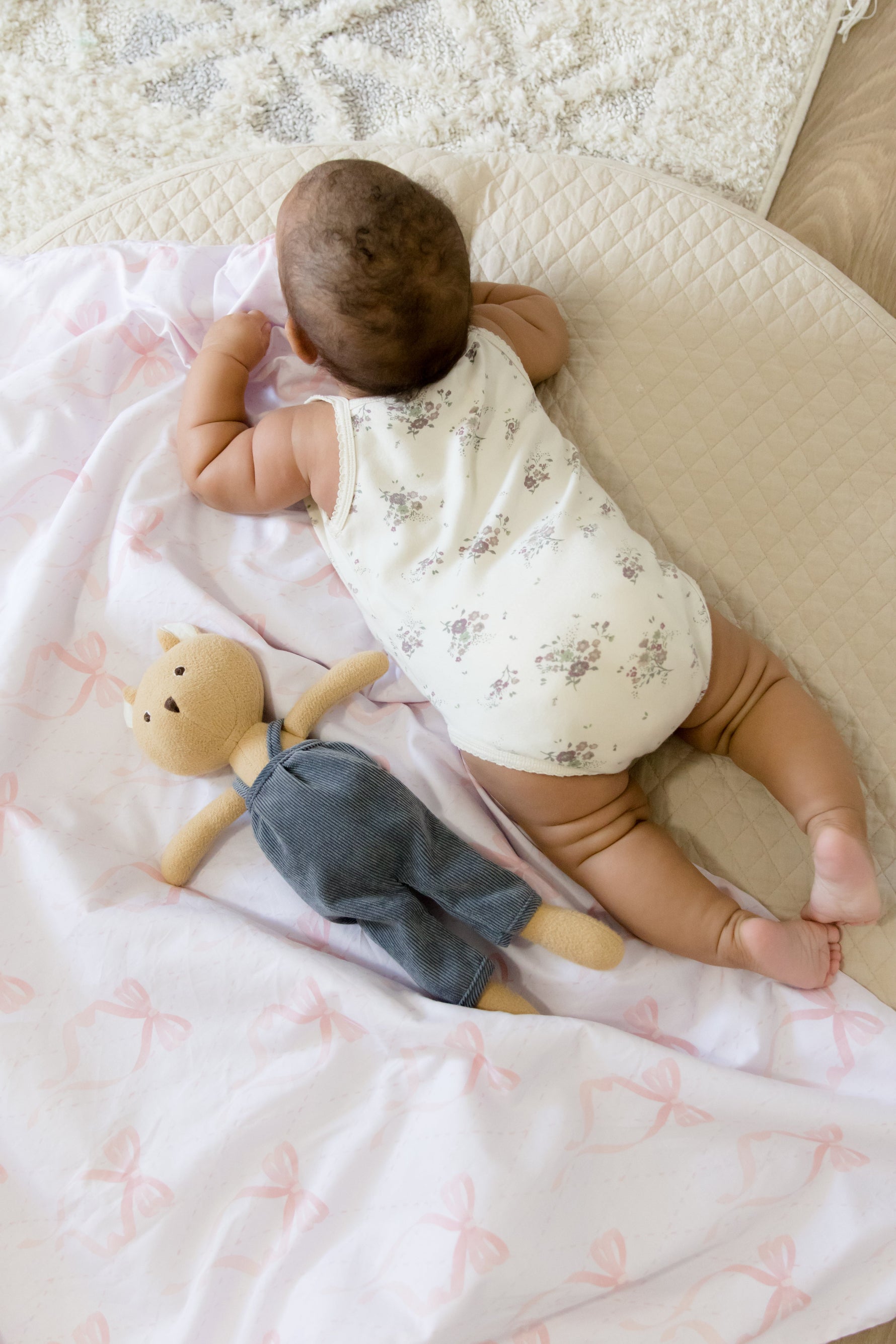 Soft white quilted baby crib blanket with delicate ribbon bow details, folded neatly in a nursery.