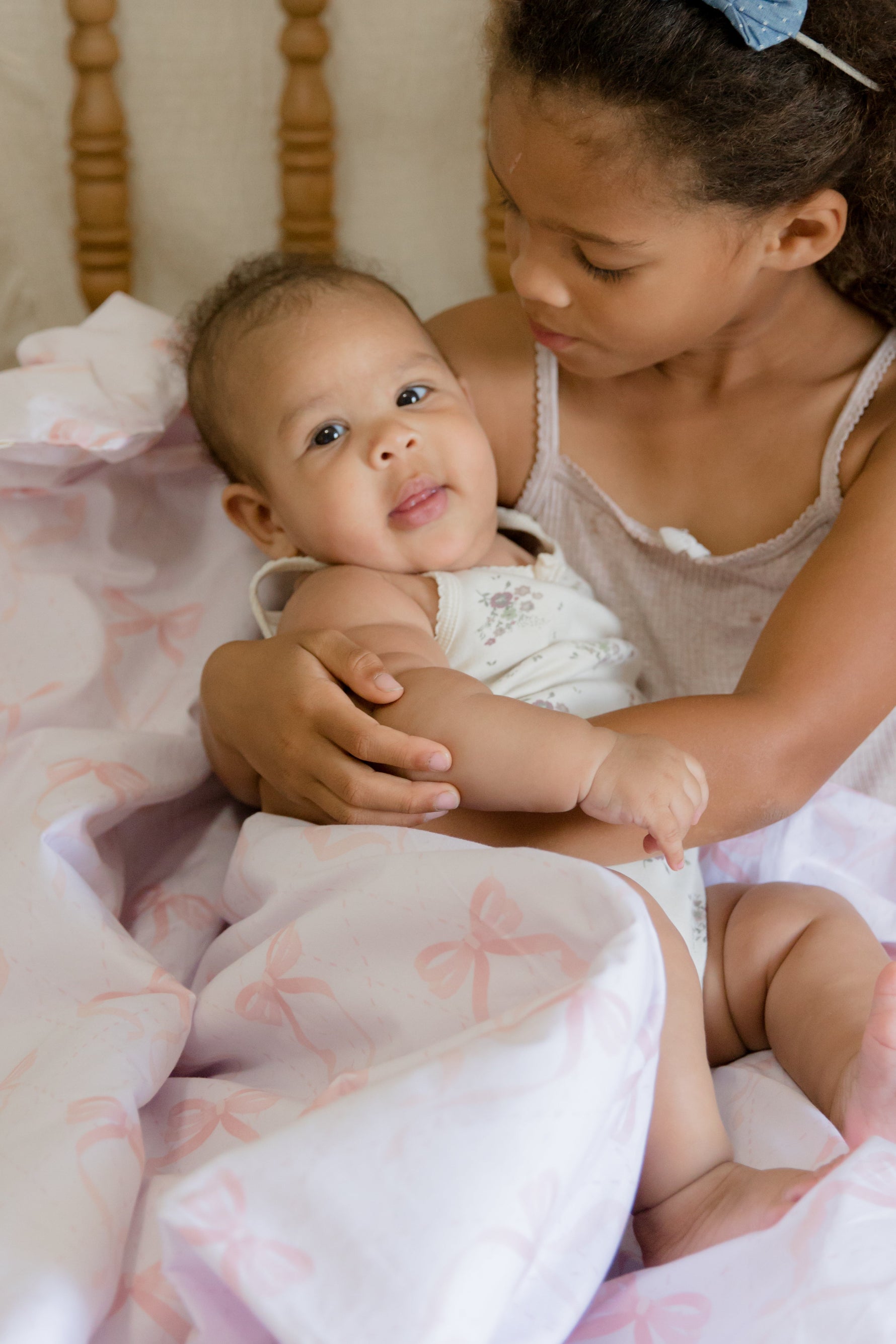 Soft white quilted baby crib blanket with delicate ribbon bow details, folded neatly in a nursery.