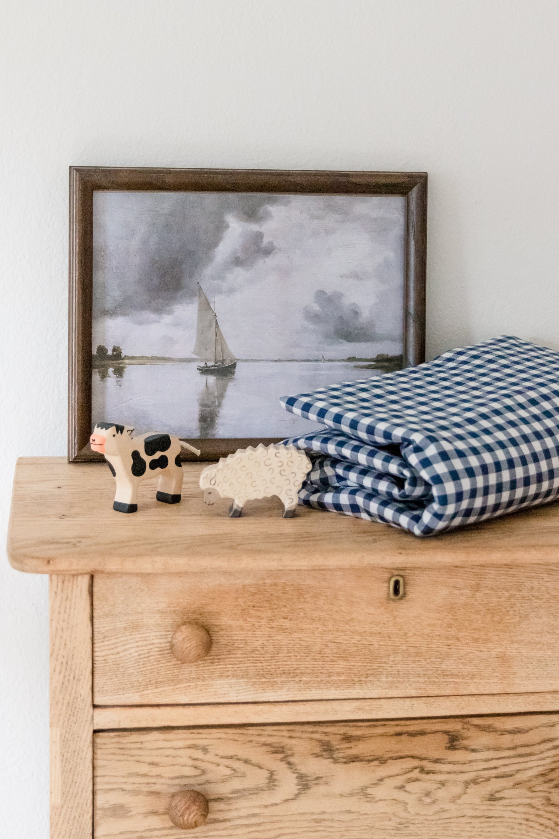 Little Mae & Co organic navy gingham quilted crib blanket draped over a white crib.