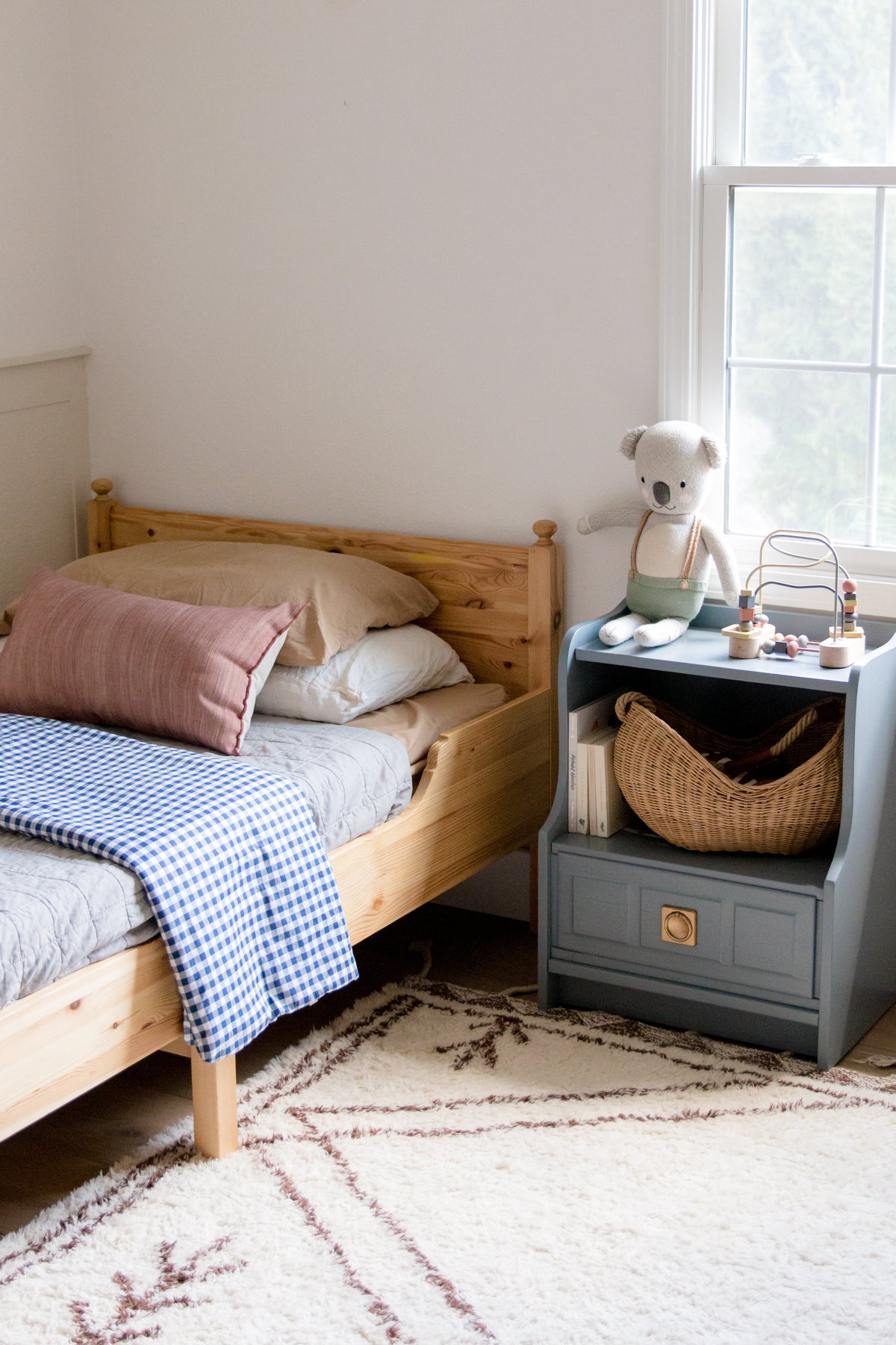 Little Mae & Co organic navy gingham quilted crib blanket draped over a white crib.