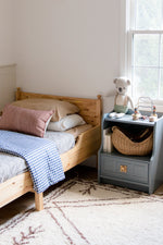Little Mae & Co organic navy gingham quilted crib blanket draped over a white crib.