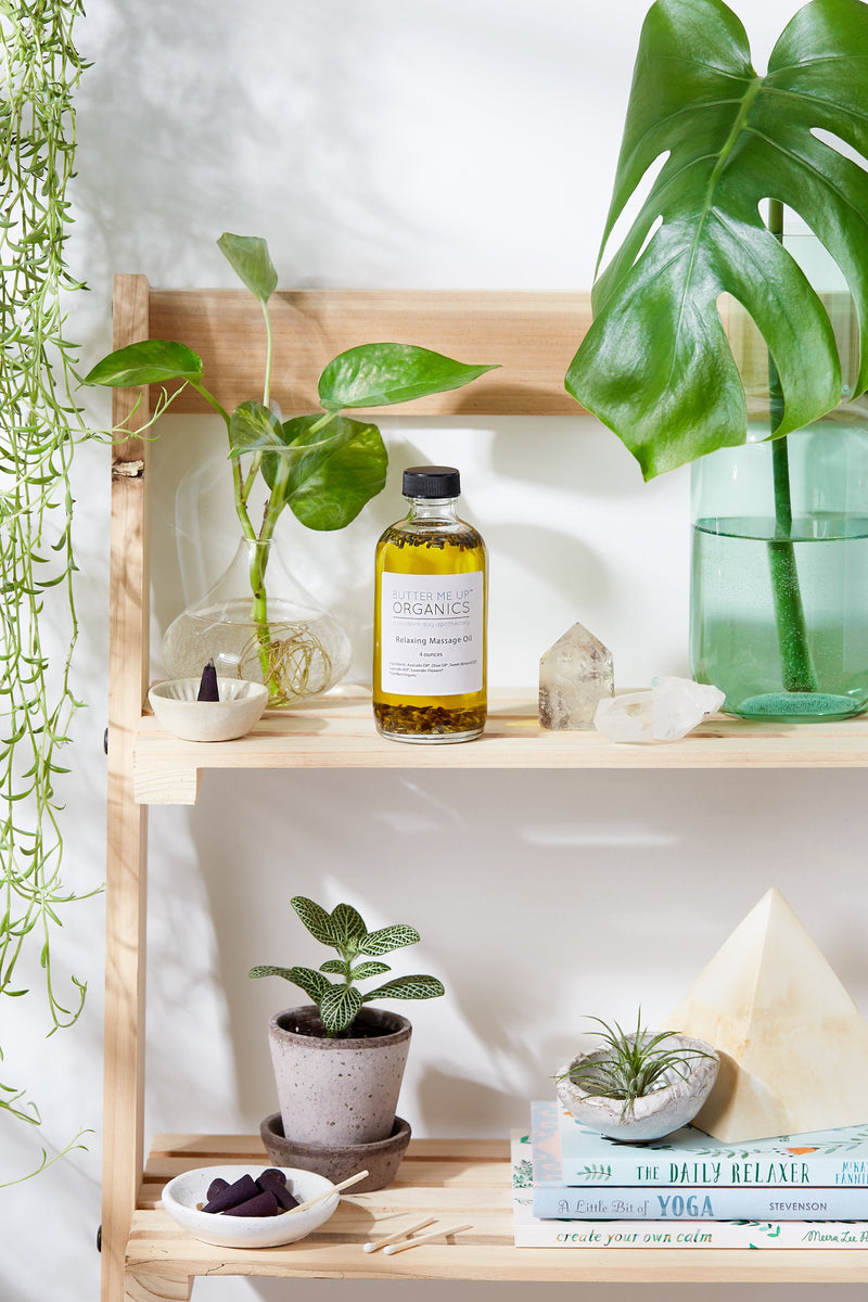 Relaxing Massage Oil on shelf with plants and books.