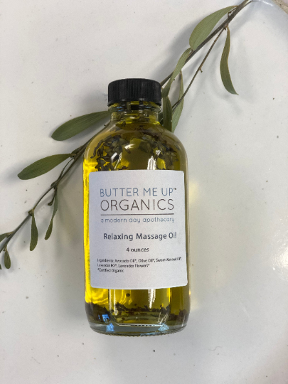 Relaxing Massage Oil in a glass bottle with organic ingredients, featuring a lavender scent, placed beside green leaves.