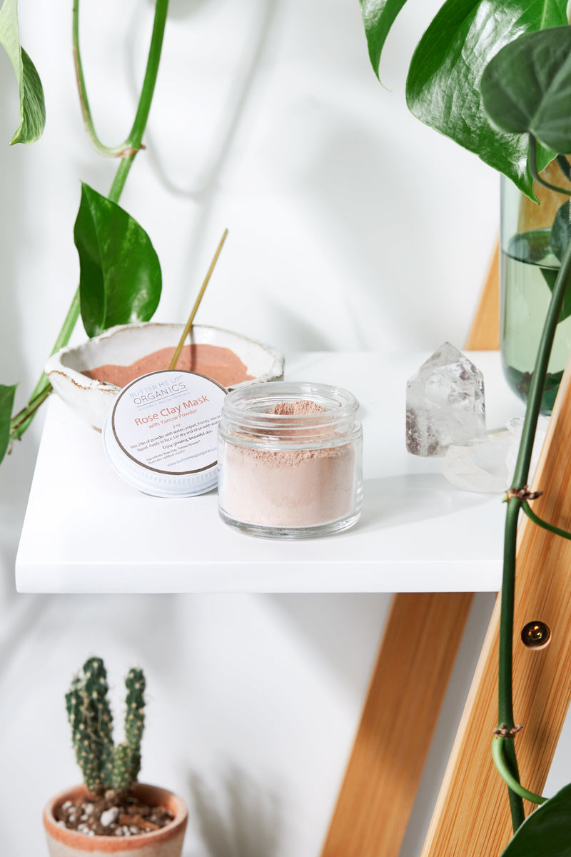 Rose Clay Face Mask in a glass jar on a white shelf with greenery.