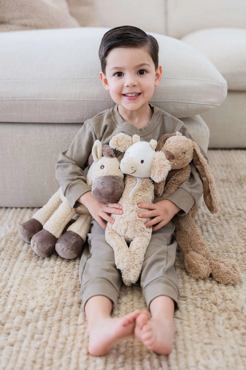 Cow Cruise no. 2 by Happy Horse plush toy, soft and colorful cuddly cow with long legs, held by a child.