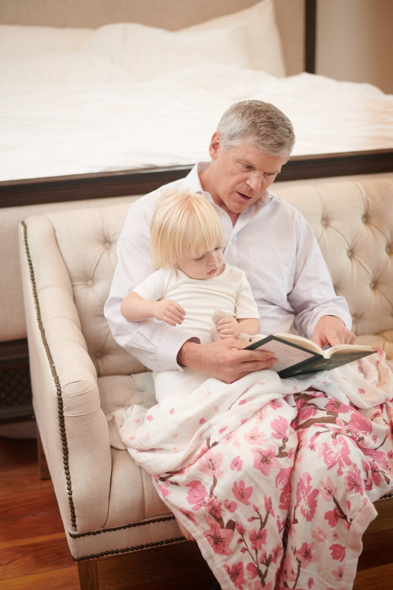 Cherry Blossom Bamboo Muslin Newcastle Blanket on a sofa, featuring a cozy and breathable design.