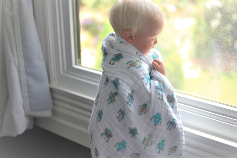 Robots Cotton Muslin blanket wrapped around a child by a window.