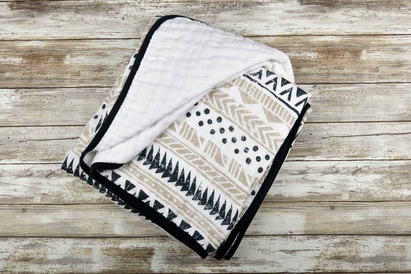 Pyramid Cotton Muslin Newcastle Blanket with tribal pattern on wooden background.