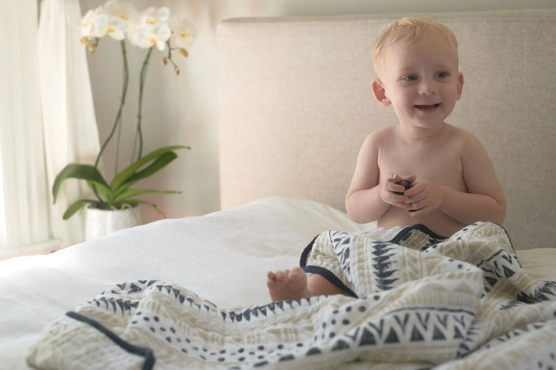 Pyramid Cotton Muslin Newcastle Blanket on bed with child, made of soft, breathable natural cotton.