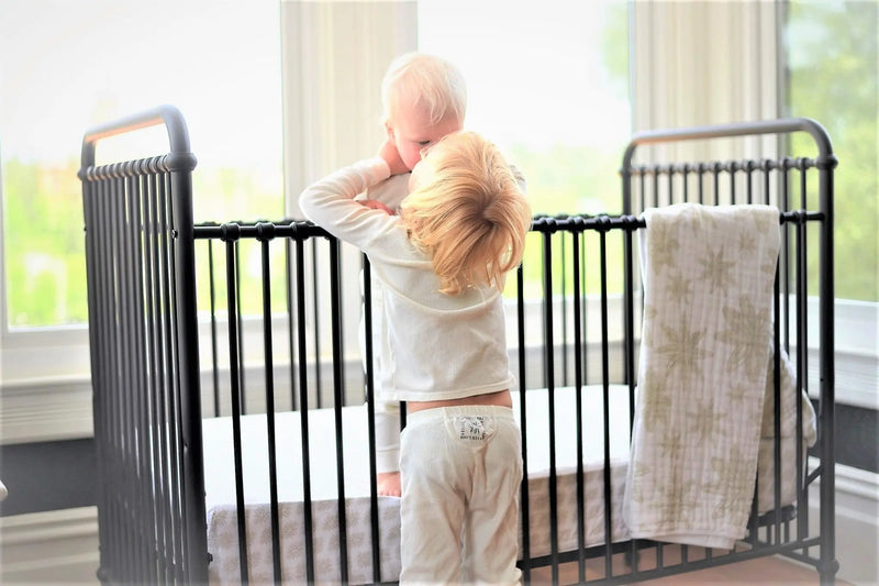 Boho Fields Cotton Muslin Newcastle Blanket draped on a crib in a cozy nursery setting.