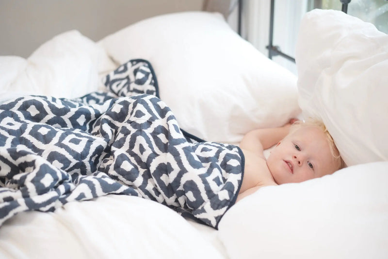 Moroccan Blue Cotton Muslin Newcastle Blanket cozy and breathable on bed.