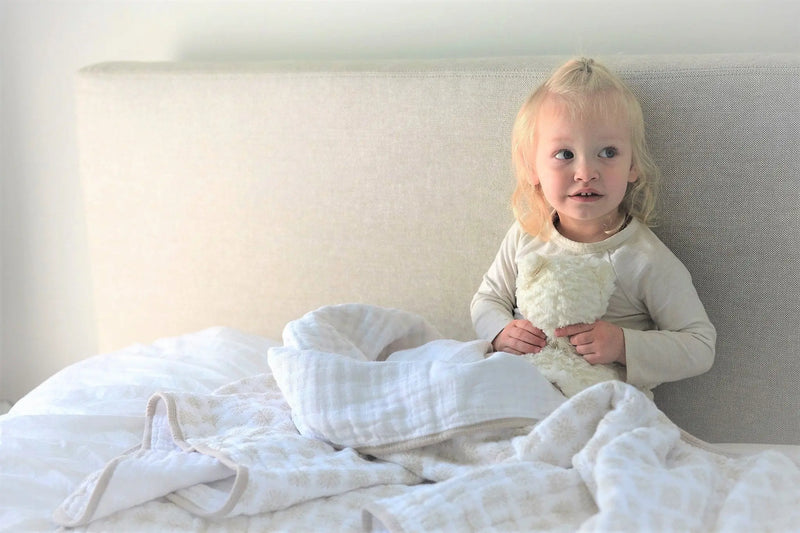 Child snuggling with Flower Child Cotton Muslin Newcastle Blanket.