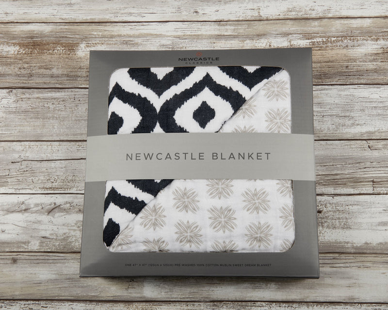 Morrocan Blue And Flower Child cotton muslin Newcastle blanket in packaging on wooden surface.