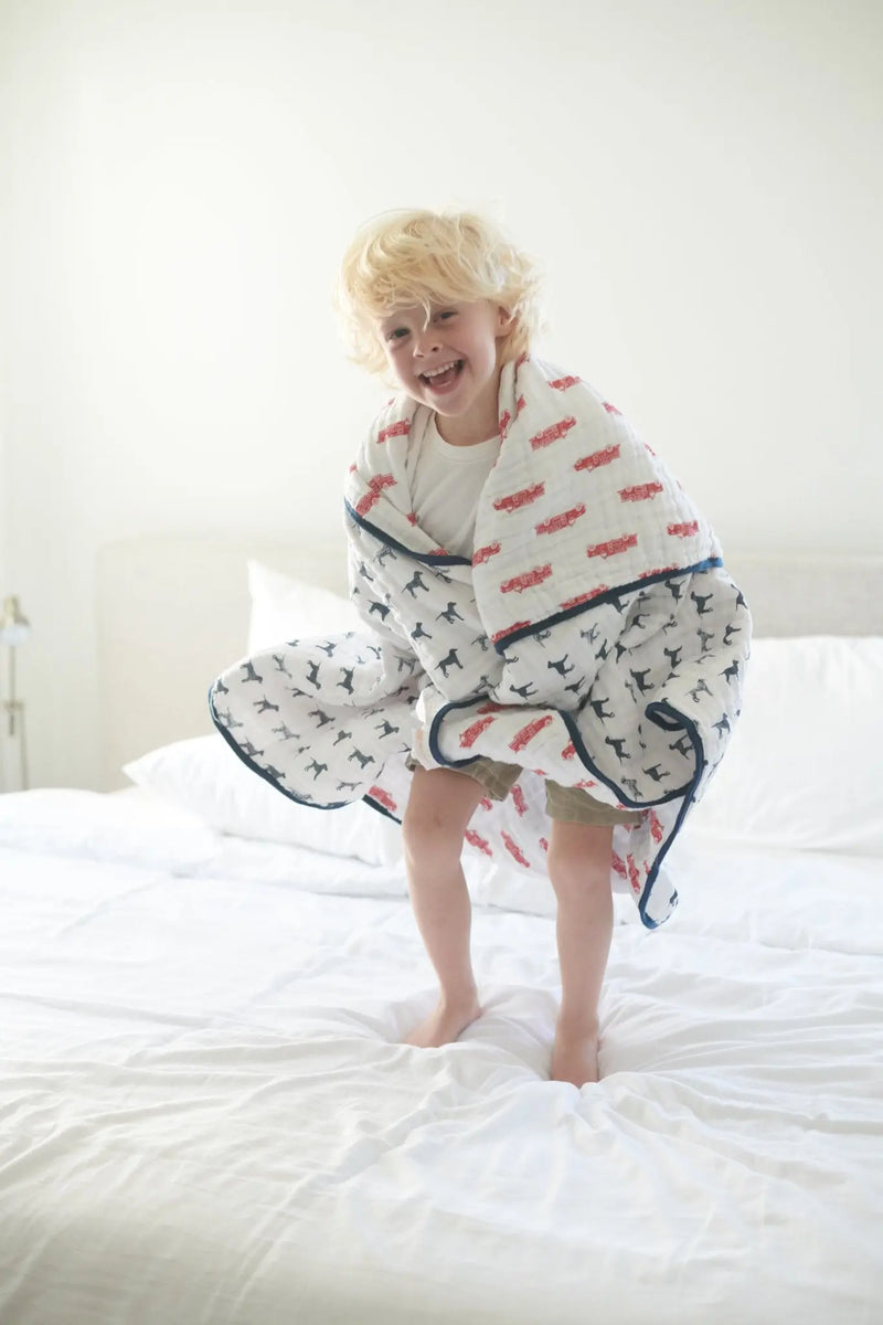 Child wrapped in a fire truck and Dalmatian patterned cotton muslin Newcastle blanket.