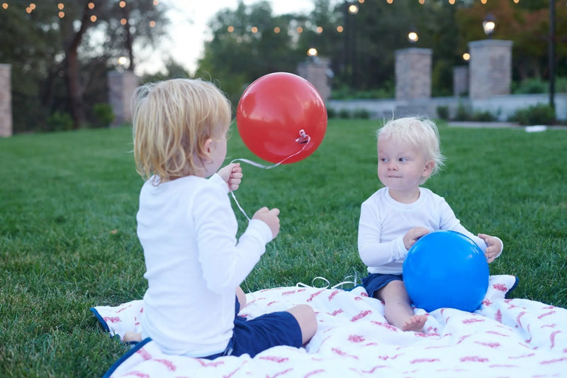 Children playing with balloons on a Fire Truck and Dalmatian Cotton Muslin Newcastle Blanket outdoors.