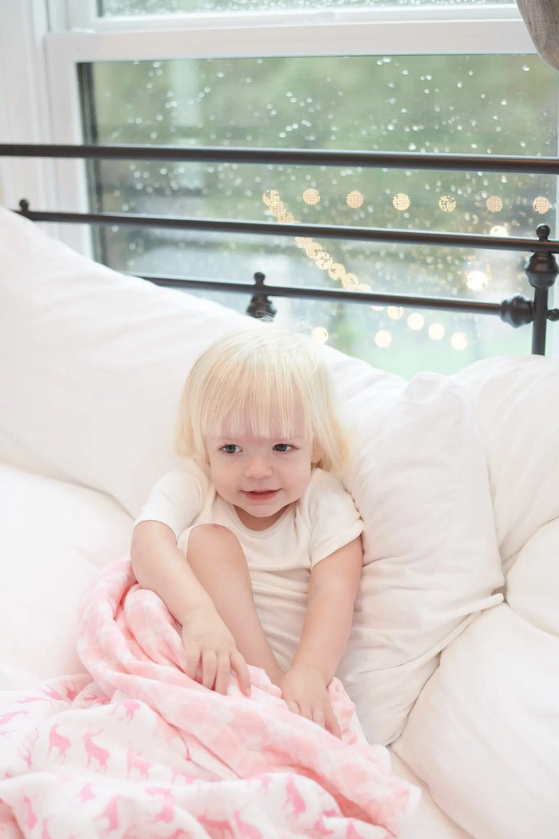 Pink deer and primrose pink plaid cotton muslin blanket on bed.