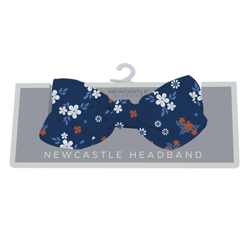Serenity Floral Bamboo Baby Headband with white and orange flowers on a dark blue background.