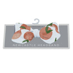 Baby headband in warm carnelian peach with a small peaches print, tied in a soft knot