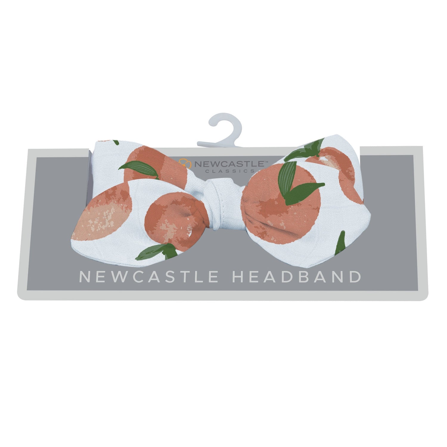 Baby headband in warm carnelian peach with a small peaches print, tied in a soft knot