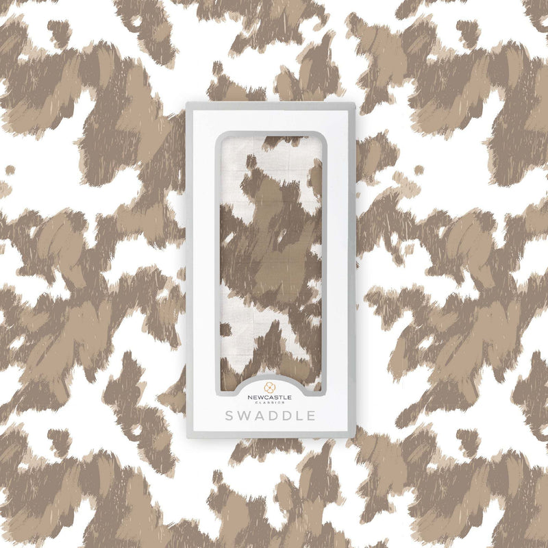 Yellowstone Cowhide Bamboo Swaddle in packaging with brown and white cowhide pattern, made from natural bamboo muslin.