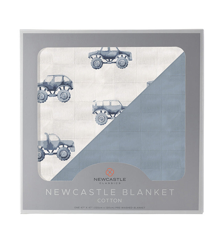 Indigo Monster Trucks and Blue Fog Cotton Newcastle Blanket in packaging, featuring breathable cotton muslin and monster truck design.