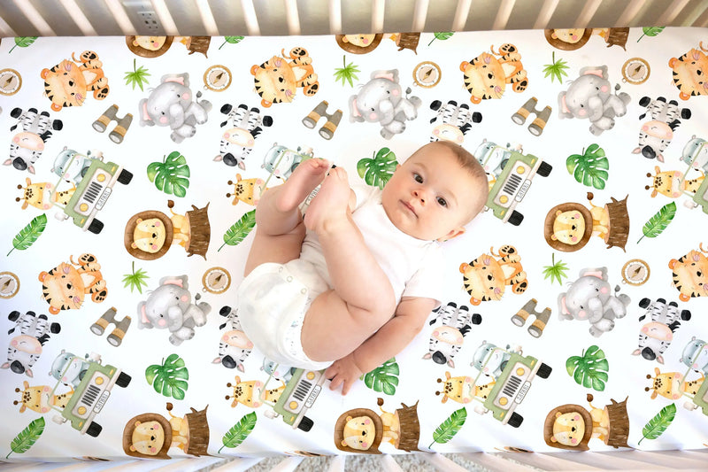Fitted crib sheet with safari animal pattern, featuring baby on soft fabric.